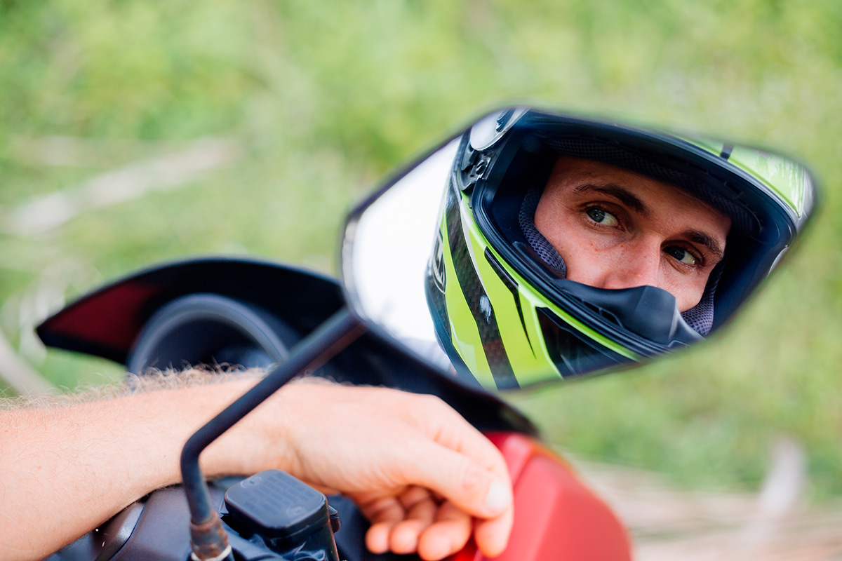 Motorcyclist looking himself from the side mirror of a motorcycle